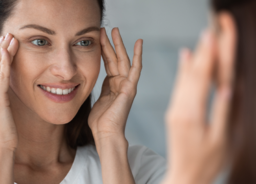 Woman looking at her face in the mirror after Dysport® treatments