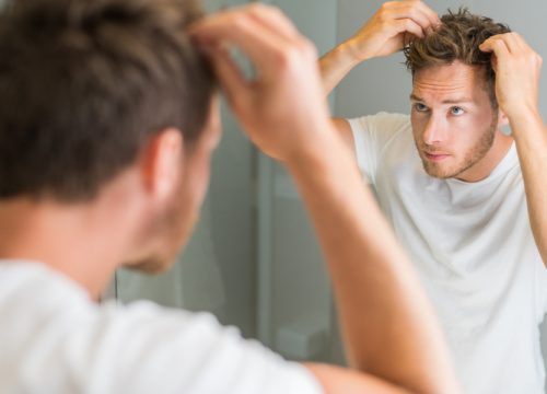 Man looking in the mirror after PRP Hair Restoration