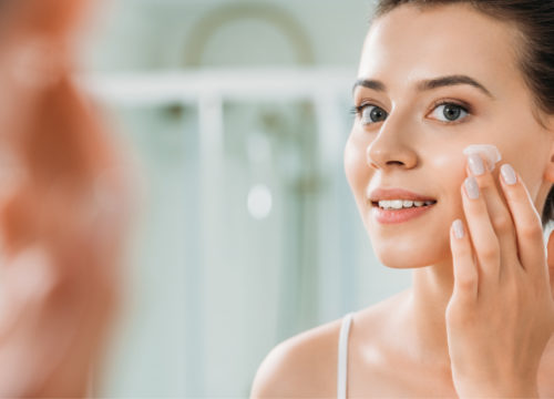 Woman adding medical-grade skincare products to her face