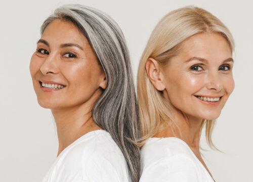 Mature multiracial women with gray hair wearing t-shirts smiling at camera isolated over white background
